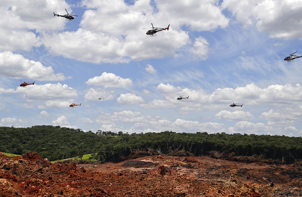 Helicopters hover over an iron ore mining complex to release thousands of flower petals paying homage to the 110 victims killed and 238 who are still missing after a mining dam collapsed there a week ago, in Brumadinho, Brazil, Feb. 1, 2019. The tragedy also stoked protests from Brazilian indigenous groups who contest the misuse and clearing of indigenous lands, often on religious grounds. (AP Photo/Andre Penner)