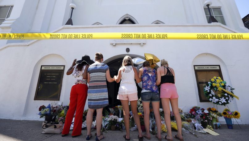 FILE - In this June 18, 2015, file photo, a group of women pray together at a makeshift memorial on the sidewalk in front of the Emanuel AME Church, in Charleston, S.C. Dylann Roof, shot and killed nine people while they were in a bible study at the church. A study released Monday, June 4, 2018, by the Southern Poverty Law Center shows about 110 Confederate monuments have been removed nationwide since 2015, when the shooting energized a movement against such memorials. (AP Photo/Stephen B. Morton, File)