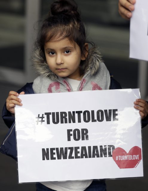 A young demonstrator holds a banner from multi-faith group 'Turn to Love' during a vigil at New Zealand House in London, Friday, March 15, 2019. Multiple people were killed in mass shootings at two mosques full of worshippers attending Friday prayers on what the prime minister called 