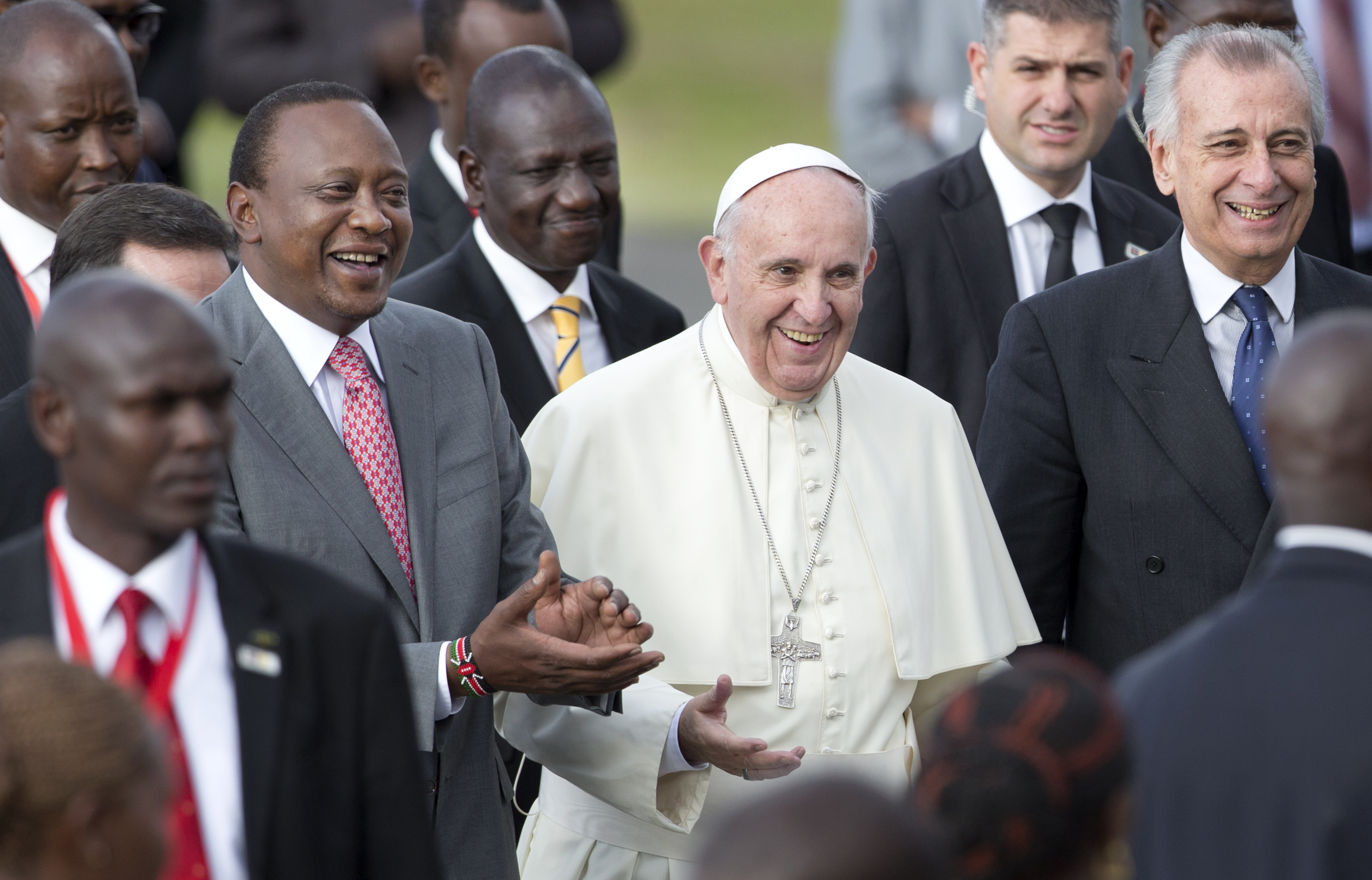 Pope Francis, center, is accompanied by Kenya's President Uhuru Kenyatta, left, and Deputy President William Ruto, center-left, on his arrival at the airport in Nairobi, Kenya Wednesday, Nov. 25, 2015. Pope Francis left Wednesday for his first-ever visit to the continent, a whirlwind pilgrimage to Kenya, Uganda and the Central African Republic, bringing a message of peace and reconciliation to an Africa torn by extremist violence. (AP Photo/Ben Curtis)