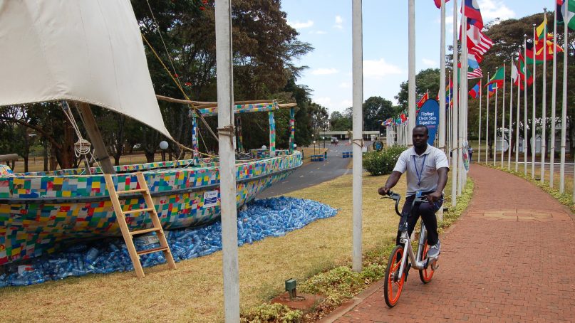 A man pedals past an art installation of a boat made from plastic waste during the United Nations Environment Assembly in Nairobi, Kenya, on March 15, 2019. RNS photo by Fredrick Nzwili