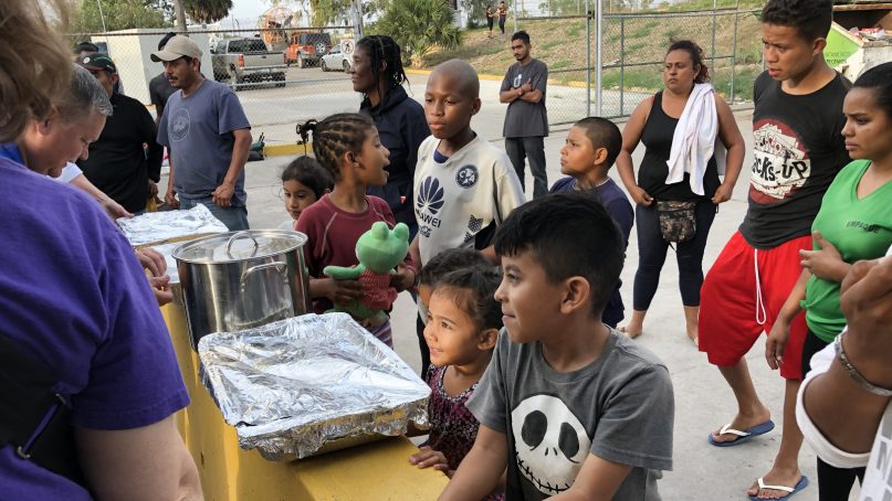 Asylum-seekers line up for a donated meal while living in limbo south of the border near Brownsville, Texas. Photo courtesy of Aaron Alexander