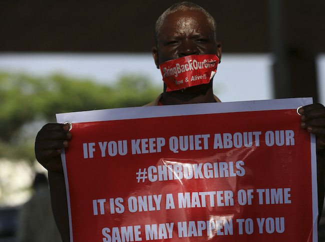 A member of the #BringBackOurGirls campaign group holds a placard under a bridge on the 140th day of the abduction of 219 schoolgirls from Government Secondary School in Chibok, Borno State, while they were sitting for their final exams, during a protest in Abuja September 1, 2014. Picture taken September 1, 2014. REUTERS/Afolabi Sotunde 