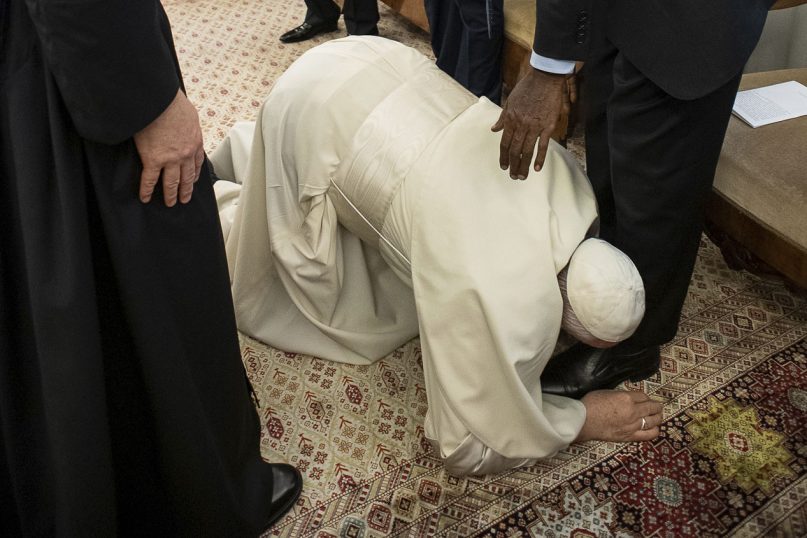 Pope Francis kneels to kiss the feet of South Sudan's Deputy President Taban Deng Gai, at the Vatican, Thursday, April 11, 2019. Pope Francis has closed a two-day retreat with South Sudan authorities at the Vatican with an unprecedented act of respect, kneeling down and kissing the feet of the African leaders. (Vatican Media via AP)