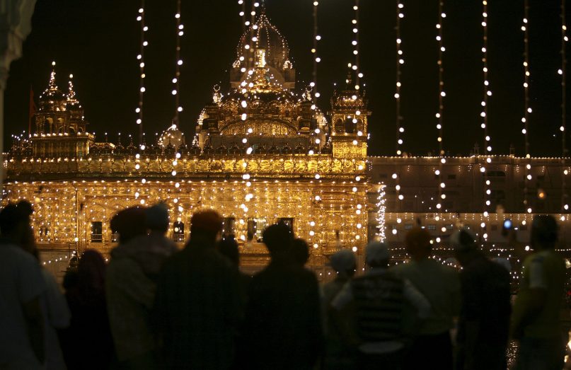 Devotees are silhouetted as they throng the illuminated Golden Temple, the holiest Sikh shrine, on the occasion of Vaisakhi, in Amritsar, India, Tuesday, April 14, 2009. (AP Photo/Altaf Qadri)