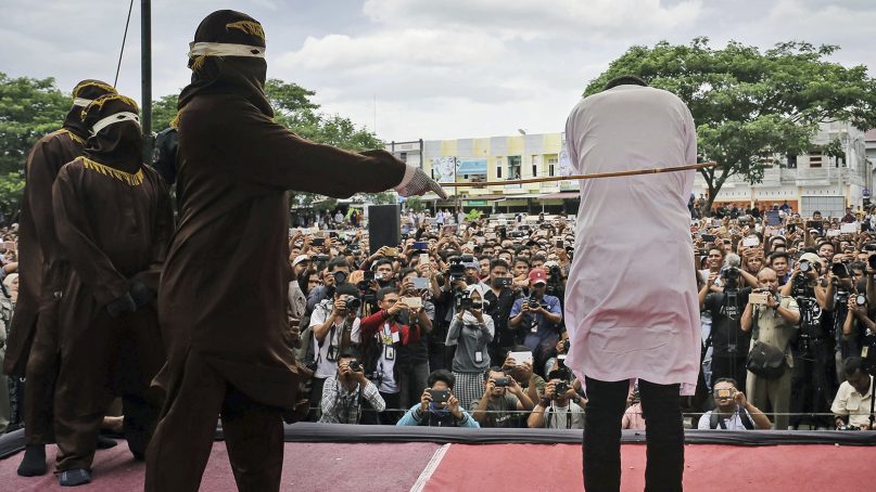 A Shariah law official whips a man convicted of gay sex during a public caning outside a mosque in Banda Aceh, Indonesia, on May 23, 2017. (AP Photo/Heri Juanda)