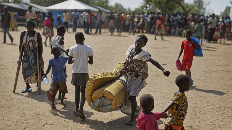 A South Sudanese refugee girl with a baby on her back carries a foam mattress to the communal tent where they will sleep, at the Imvepi reception center, where newly arrived refugees are processed before being allocated plots of land in nearby Bidi Bidi refugee settlement, in northern Uganda, on June 9, 2017. (AP Photo/Ben Curtis)