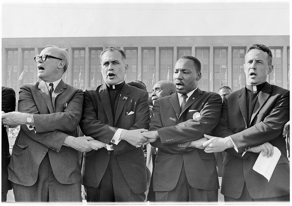 The Rev. Theodore Hesburgh, center left, holds hands with the Rev. Martin Luther King Jr. while singing "We Shall Overcome” during a civil rights rally at Soldier Field in Chicago on June 21, 1964. Photo courtesy of OCP Media