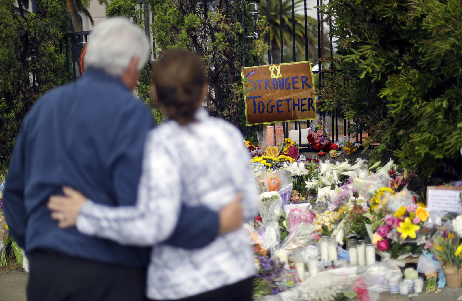 A couple embrace near a growing memorial across the street from the Chabad of Poway Synagogue in Poway, California, on April 29, 2019. A gunman opened fire two days before as about 100 people were worshipping, exactly six months after a mass shooting in a Pittsburgh synagogue. One person was killed in the Poway attack. (AP Photo/Greg Bull)