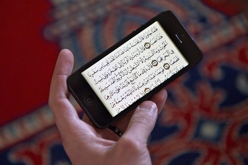 A man reads the Quran on an iPhone during a prayer service at the Islamic Society of Boston mosque on April 26, 2013, in Cambridge, Mass. (AP Photo/Robert F. Bukaty)