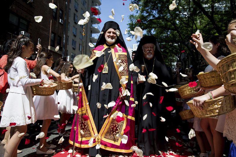 Archbishop Elpidophoros, center left, and Metropolitan Augoustinos of Germany, center right, walk toward the Archdiocesan Cathedral of the Holy Trinity for Elpidophoros' enthronement ceremony as the new archbishop for America, as young girls throw flower petals, on June 22, 2019, in New York. (AP Photo/Julius Motal)