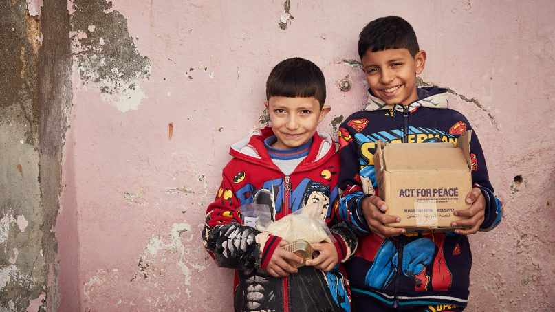 Refugee brothers Nadim, left, and Hadi hold an Act for Peace Refugee Food Ration box in Jordan in 2017. Photo by Joel Pratley, courtesy of Ration Challenge