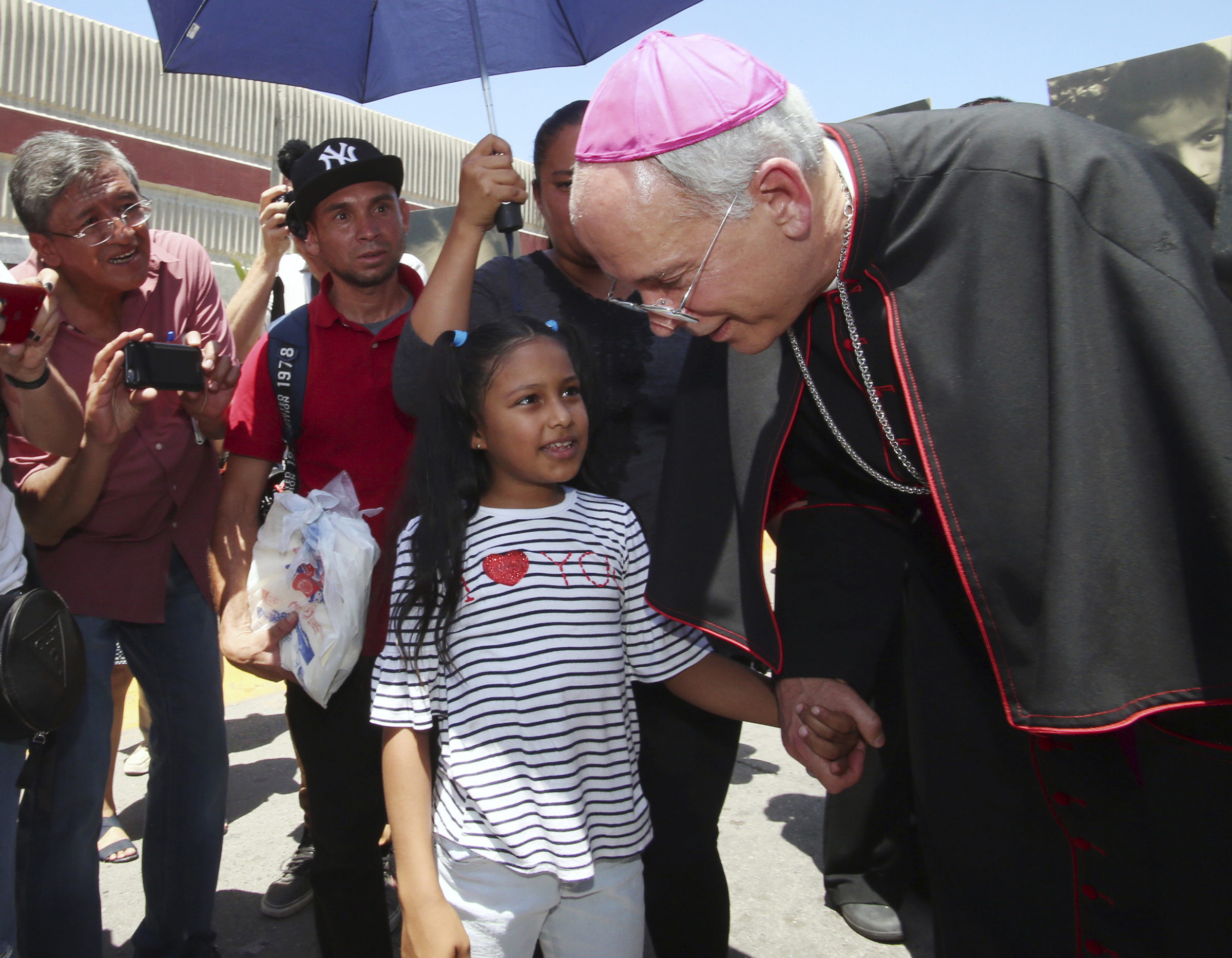 El Paso Catholic Bishop Mark Seitz talks with Celsia Palma, 9, of Honduras, as they walked to the Paso Del Norte International Port of Entry on June, 27, 2019, in Juarez, Mexico. Seitz escorted the girl, her parents and two siblings across the port of entry to U.S. immigration authorities so they could be processed into the U.S. (AP Photo/Rudy Gutierrez)