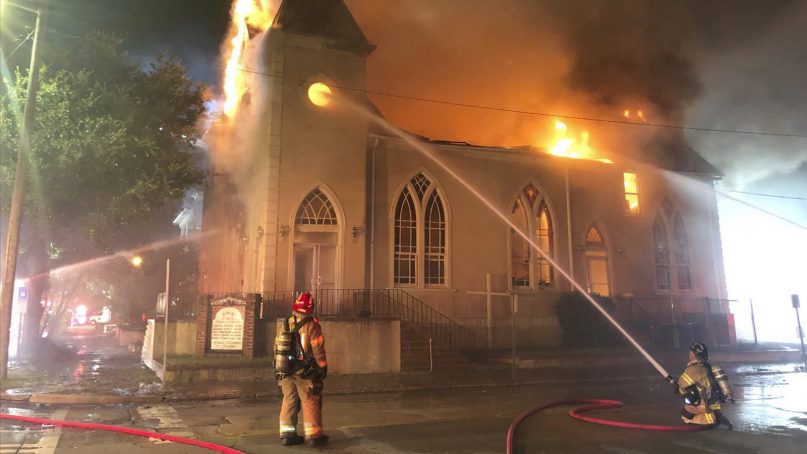 In this Sunday, July 21, 2019 photo released by the Savannah Fire Department, firefighters work to but our a fire at the  First Metropolitan Baptist Church, in Savannah, Ga. A house fire in Savannah, spread to the church whose pastor was recently accused of sexually abusing a child.  Reports say the homes and church were vacant at the time of the fire, and no injuries have been reported. (Savannah Fire Department via AP)