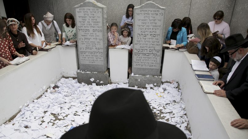 In this July 2, 2019, photo, people pray at the gravesite of Rabbi Menachem M. Schneerson in the Queens borough of New York. Men and women, young and old, make their way from around the city, the country and the world to this unassuming site to pay their respects to the life and teachings of the revered Jewish leader of the Chabad-Lubavitch movement, who died 25 years ago in June 1994. (AP Photo/Seth Wenig)