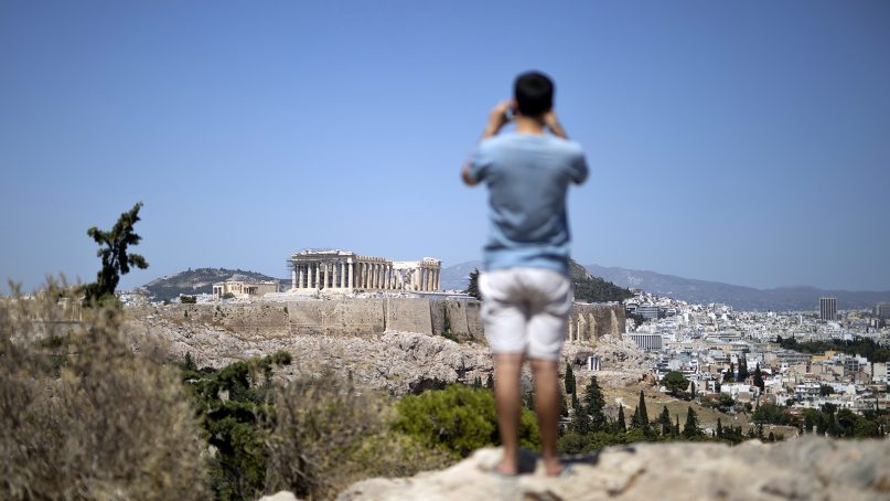 A tourist takes a picture of Acropolis hill with the ancient Parthenon temple during a hot day in Athens, on July 4, 2019. Greece's most famous archaeological site, the Acropolis in Athens, was shut down to visitors for hours because of hot weather in the capital. (AP Photo/Petros Giannakouris)