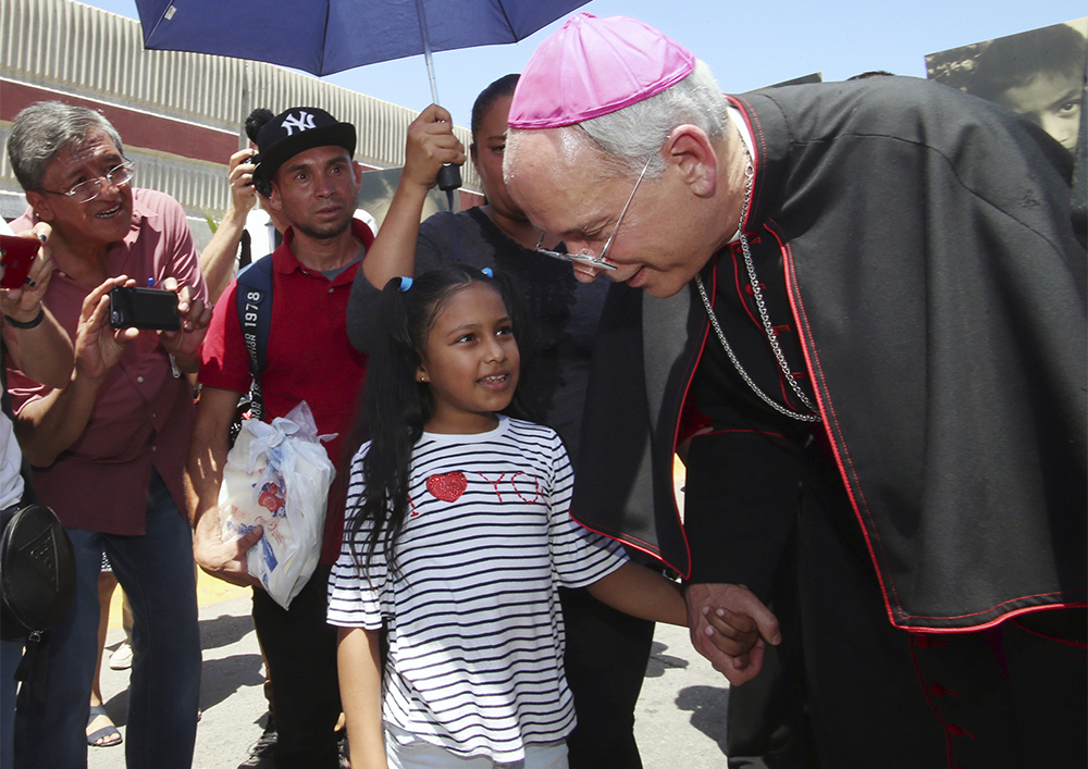 El Paso Catholic Bishop Mark Seitz talks with Celsia Palma, 9, of Honduras, as they walked to the Paso Del Norte International Port of Entry on June, 27, 2019, in Juarez, Mexico. Seitz escorted the girl, her parents and two siblings across the port of entry to U.S. immigration authorities so they could be processed into the U.S. (AP Photo/Rudy Gutierrez)