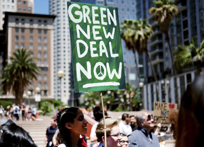 Climate change activists holding signs join in on a rally supporting the 