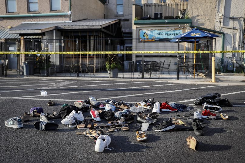 Shoes are piled outside the scene of a mass shooting, including Ned Peppers bar, Sunday, Aug. 4, 2019, in Dayton, Ohio. Several people in Ohio have been killed in the second mass shooting in the U.S. in less than 24 hours, and the suspected shooter is also deceased, police said. (AP Photo/John Minchillo)