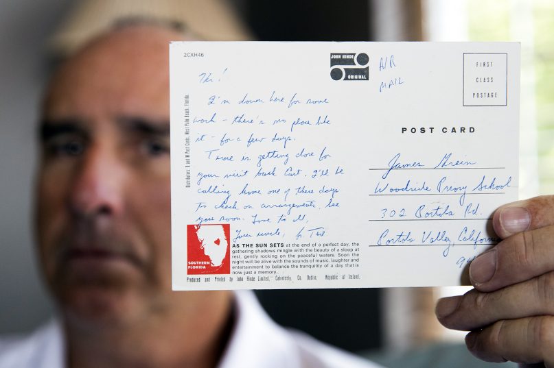 James Grein, 61, at his house in Sterling, Va., on July 26, 2019, holds a Florida postcard sent to him when he was 15 years old by now-defrocked Cardinal Theodore McCarrick. Letters and postcards McCarrick wrote to three men he allegedly sexually abused and harassed show how he groomed his victims, experts say. (AP Photo/Manuel Balce Ceneta)