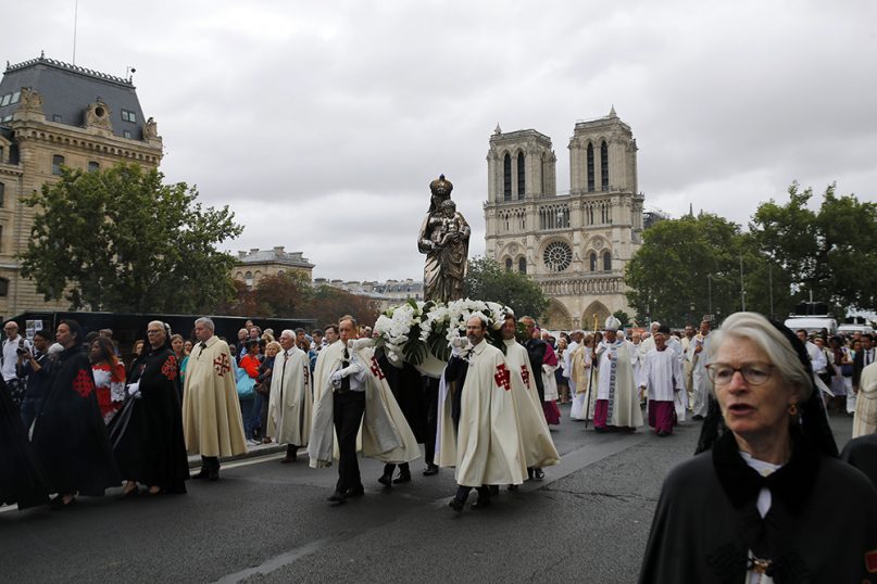 Catholic clergymen and pilgrims take part in an emotional procession with a statue of the Virgin Mary passing the fire-ravaged Notre-Dame de Paris cathedral to celebrate the Feast of the Assumption on Aug. 15, 2019. The statue was rescued from the blaze at the cathedral a few months before. (AP Photo/Francois Mori)