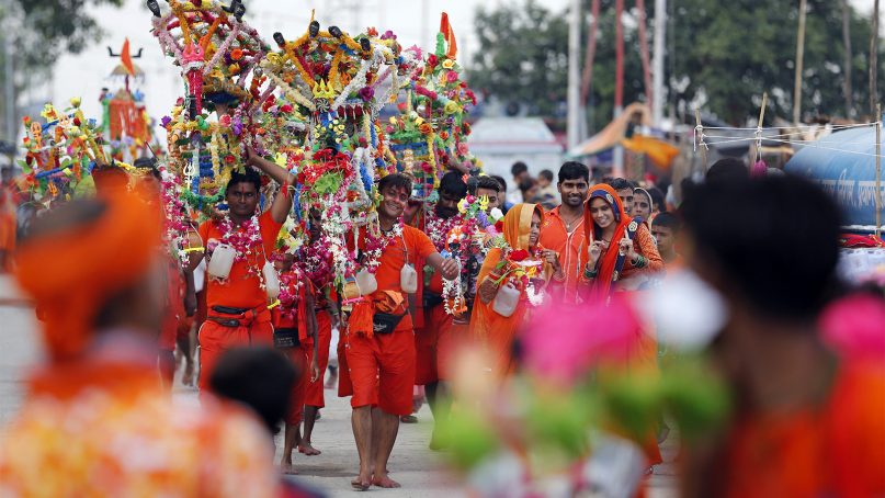 Hindu pilgrims, known as Kanwarias, walk near the banks of the Ganges River in Prayagraj, India, on July 25, 2019. Kanwarias are devotees performing a ritual pilgrimage in which they walk the roads of India, clad in saffron, and carrying ornately decorated canisters of sacred water from the Ganges River over their shoulders to take back to Hindu temples in their hometowns, during the Hindu lunar month of Shravana.(AP Photo/Rajesh Kumar Singh)