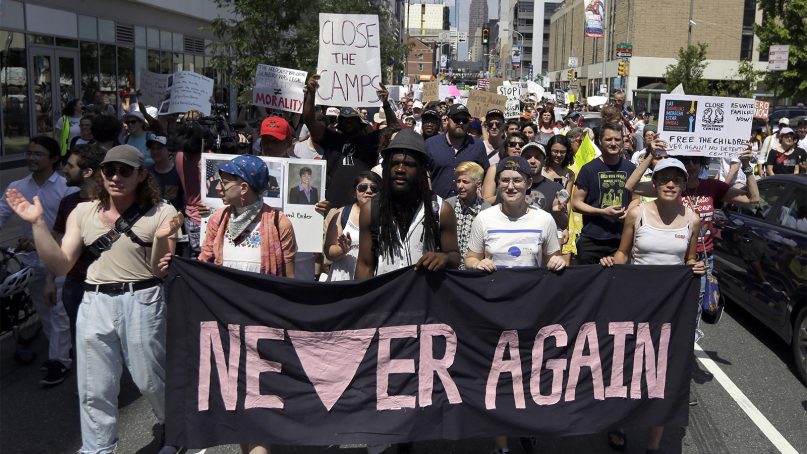 Protesters assembled by a majority Jewish group walk through traffic as they make their way to Independence Mall on July 4, 2019, in Philadelphia. Hundreds gathered during the city's traditional Fourth of July parade to protest the treatment of immigrants and asylum-seekers. (AP Photo/Jacqueline Larma)