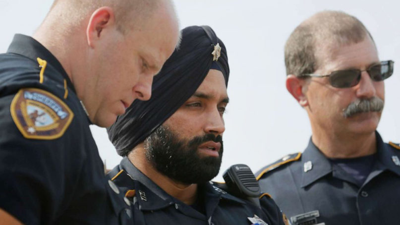 In this Aug. 30, 2015, photo, Harris County Sheriff's Deputy Sandeep Dhaliwal, center, grieves with Deputies Dixon, left, and Seibert, right, at a memorial for Deputy Darren Goforth, at the Chevron where he was killed, in Houston. (Jon Shapley/Houston Chronicle via AP)