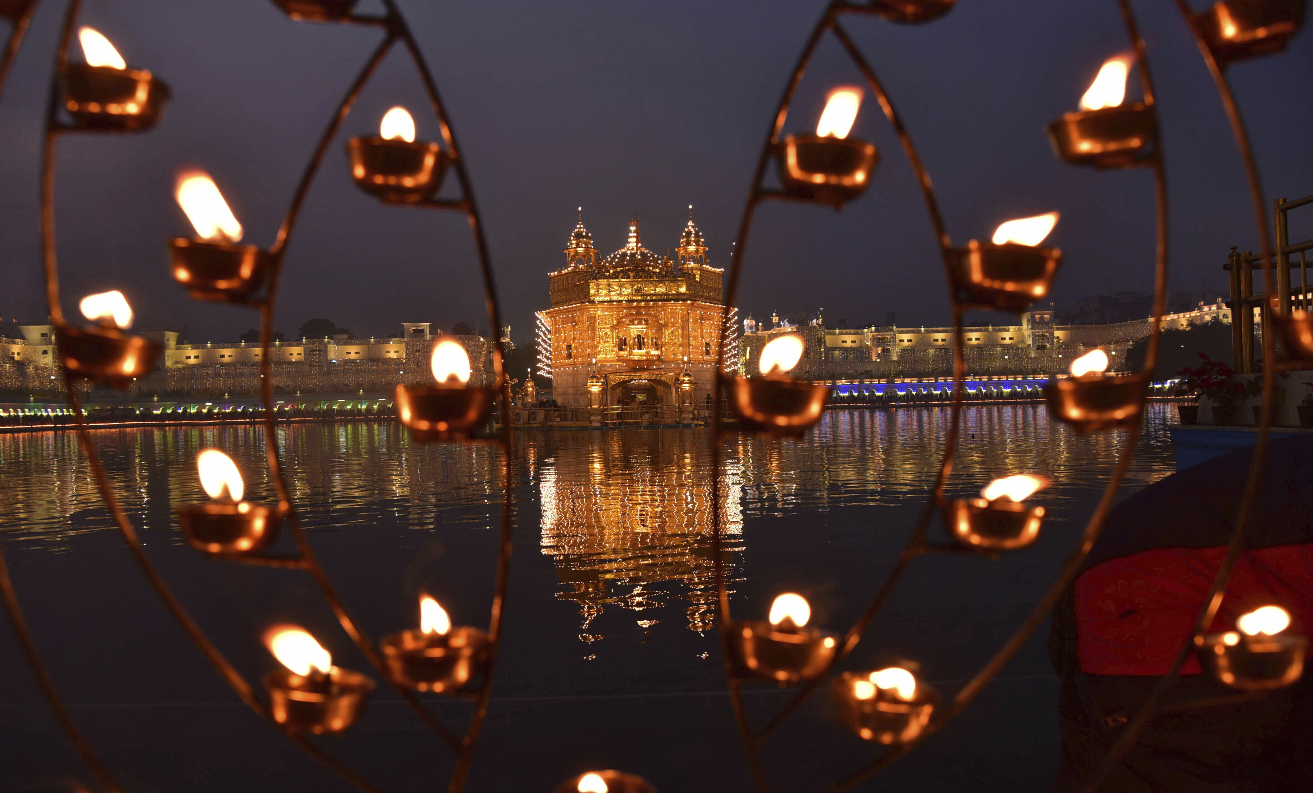 Lamps lit by devotees shine in front of the illuminated Golden Temple, the holiest of Sikh shrines, on the birth anniversary of Guru Nanak in Amritsar, India, Tuesday, Nov. 12, 2019. Sikhs across the world are marking the birth anniversary of Guru Nanak, the founder of Sikhism and first guru. (AP Photo/Prabhjot Gill)