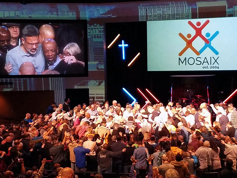 A large group prays around John Perkins during the Mosaix conference on Nov. 7, 2019, in Keller, Texas. RNS photo by Adelle M. Banks