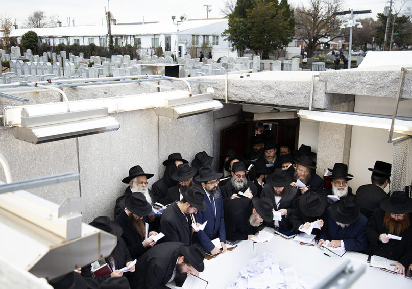 Hasidic leaders read personal notes and prayers at the resting place of the late Rabbi Menachem Mendel Schneerson at Montefiore Cemetery in New York, on Nov. 22, 2019. (AP Photo/Jessie Wardarski)