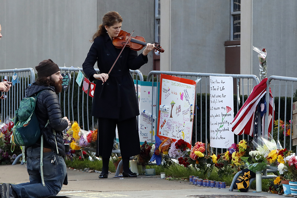 Monique Mead plays her violin on the sidewalk outside the Tree of Life synagogue in Pittsburgh on Sunday, Oct. 27, 2019, the first anniversary of the shooting at the synagogue that killed 11 worshippers. (AP Photo/Gene J. Puskar)