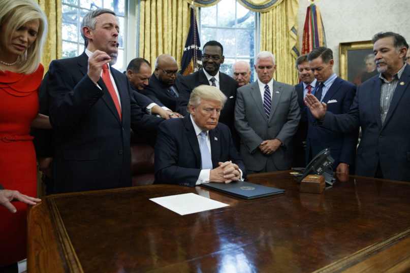 In this Sept. 1, 2017, file photo, religious leaders pray with President Donald Trump after he signed a proclamation for a national day of prayer to occur on Sept. 3, 2017, in the Oval Office of the White House in Washington. (AP Photo/Evan Vucci, File)