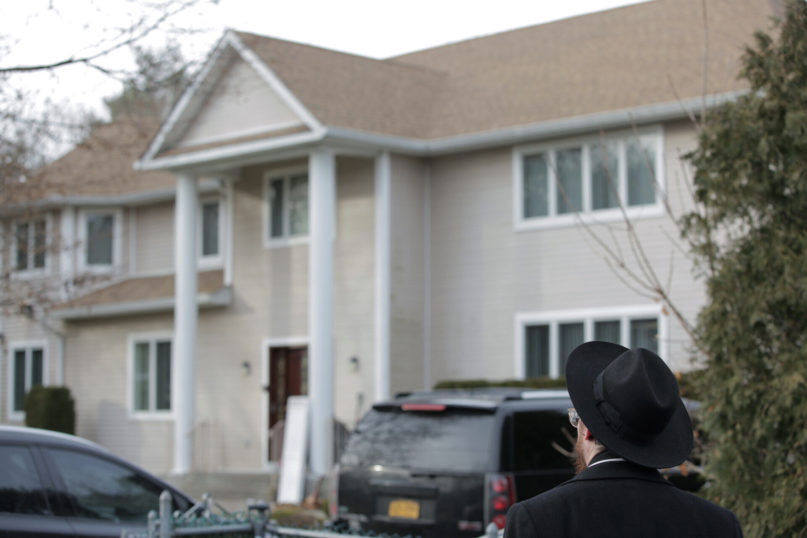 An onlooker stands outside a rabbi's residence in Monsey, N.Y., Sunday, Dec. 29, 2019, following a stabbing Saturday night during a Hanukkah celebration. (AP Photo/Julius Constantine Motal)