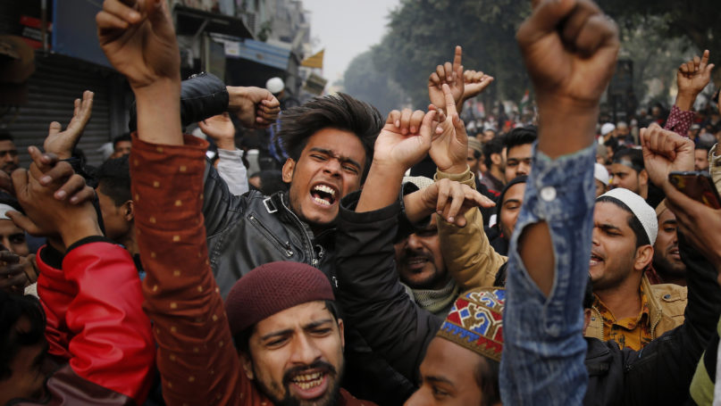 Indians shout slogans in front of a police barricade to protest against the Citizenship Amendment Act in New Delhi, India, Friday, Dec. 20, 2019. Police banned public gatherings in parts of the Indian capital and other cities for a third day Friday and cut internet services to try to stop growing protests against a new citizenship law that have left eight people dead and more than 4,000 others detained. (AP Photo/Altaf Qadri)