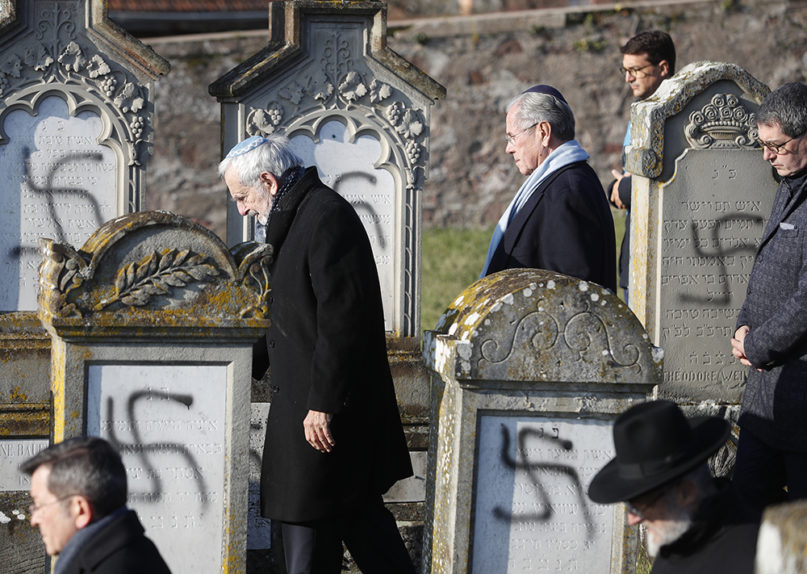 Members of the Jewish community walk amid vandalized tombs in the Jewish cemetery of Westhoffen, west of the city of Strasbourg, eastern France, on Dec. 4, 2019. Regional authorities in eastern France say vandals have scrawled anti-Semitic inscriptions, including swastikas spray-painted in black, on 107 tombs in a Jewish cemetery. (AP Photo/Jean-Francois Badias)