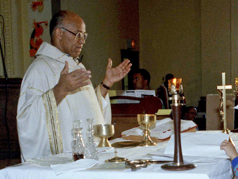 In this Jan. 28, 1991, file photo, the Rev. George Clements receives the names of relatives serving in the Persian Gulf War from his parishioners in Chicago. Clements, the Chicago priest whose civil rights and social justice activism led to a television movie about his career, died Nov. 25, 2019, at the age of 87. (AP Photo/Fred Jewell)