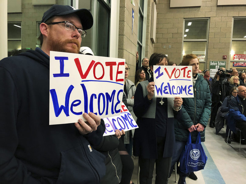 Residents in support of continued refugee resettlement hold signs at a meeting in Bismarck, N.D., Monday, Dec. 9. 2019. Several church leaders urged Burleigh County not to be the nation's first to refuse new refugees since President Donald Trump ordered that states and counties should have the power to do so. (AP Photo/James MacPherson)