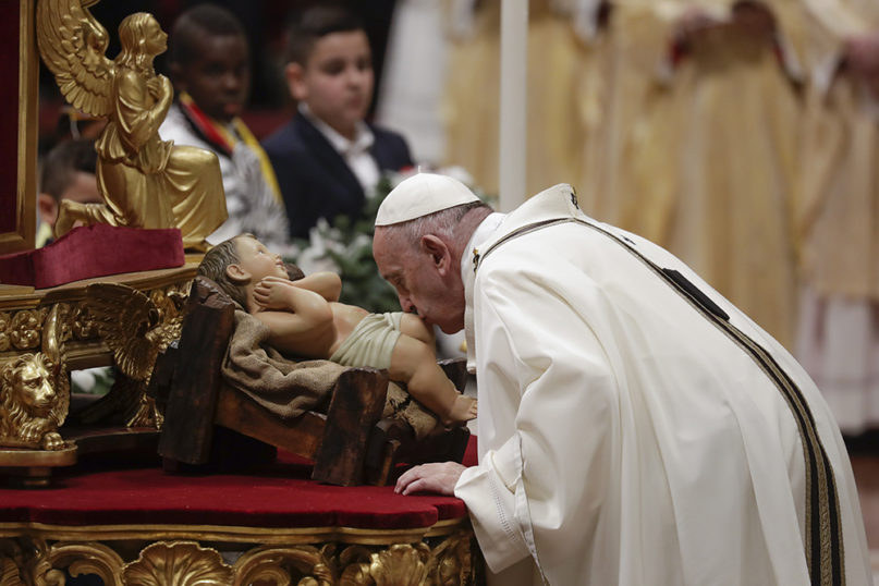 Pope Francis kisses a statue of baby Jesus as he celebrates Christmas Eve Mass in St. Peter's Basilica at the Vatican on Dec. 24, 2019. (AP Photo/Alessandra Tarantino)