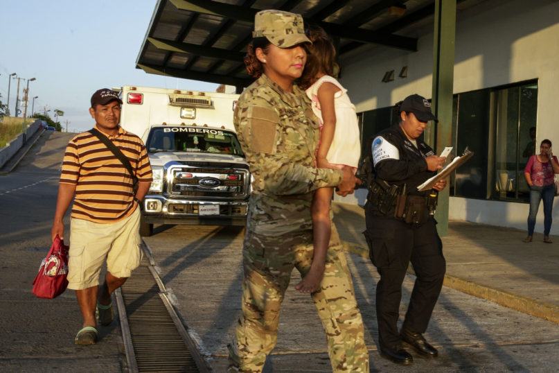 Jose Gonzalez, left, follows his 5-year-old daughter, carried by a police officer, as they leave a hospital in Santiago, Panama, Thursday, Jan. 16, 2020. Gonzalez's wife and five of their children are among seven people killed in a religious ritual in the Ngabe Bugle indigenous community. According to local prosecutor Rafael Baloyes indigenous residents were rounded up by lay preachers and tortured, beaten, burned and hacked with machetes to make them 