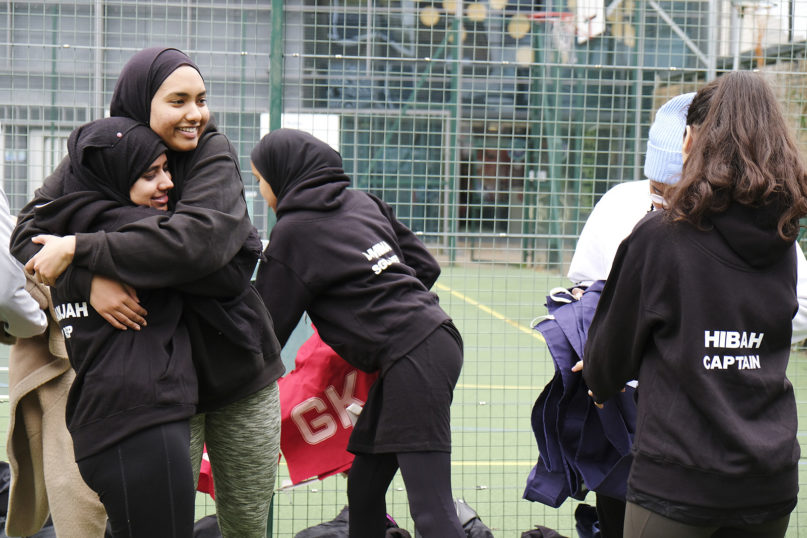 Khadijah Sufi, left, and Sumayyah Akhter, members of the ISOC Netball team, hug before a match on Jan. 26, 2020, at the Colombo Courts in London. RNS photo by Aysha Khan