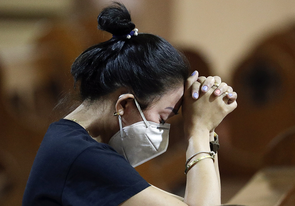 A woman wears a protective mask during a Mass in the Chinatown area of Manila, Philippines, Thursday, Jan. 30, 2020. The Catholic Bishops' Conference of the Philippines said communions must be placed on the hands instead of putting it in the mouth of churchgoers as a precautionary measure in masses to help prevent the spread of the new coronavirus in this predominantly Roman Catholic country. Health Secretary Francisco Duque confirmed the Philippines' first case of a new virus that has infected thousands in China. (AP Photo/Aaron Favila)