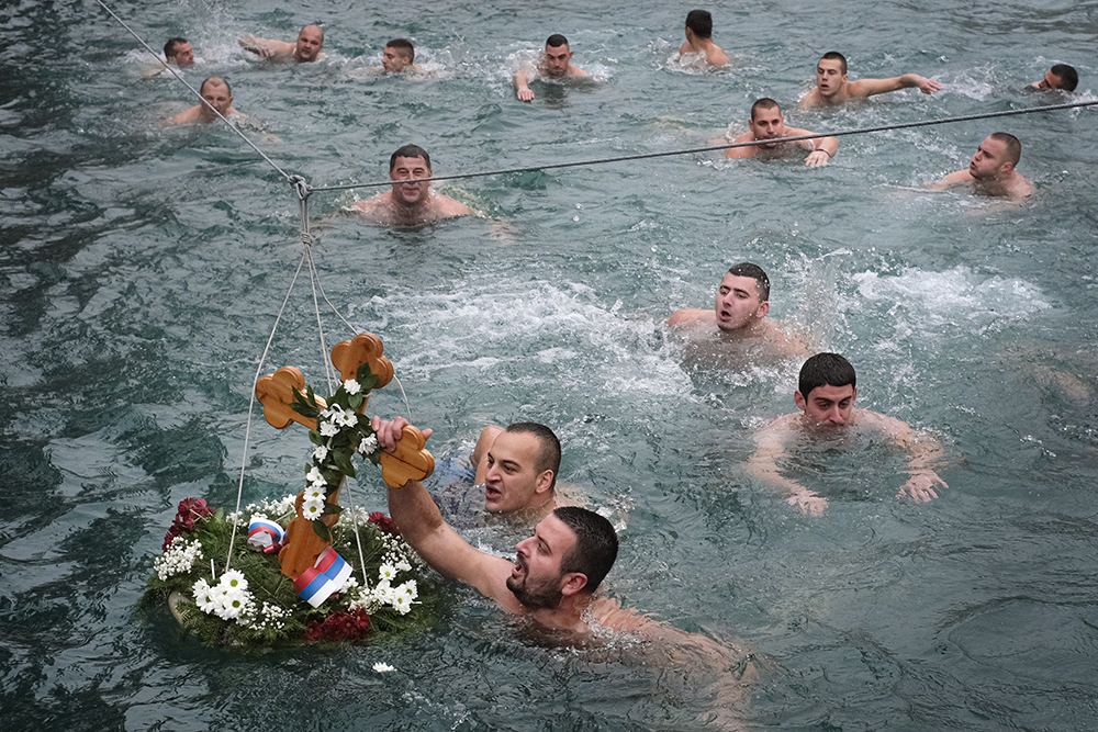 Men swim in the icy waters of the Drina River in Visegrad, Bosnia, Sunday, Jan. 19, 2020, competing to reach a wooden cross. Serbian Orthodox Church followers plunged into icy rivers and ponds across the country to mark the upcoming Epiphany, cleansing themselves with water deemed holy for the day. (AP Photo)