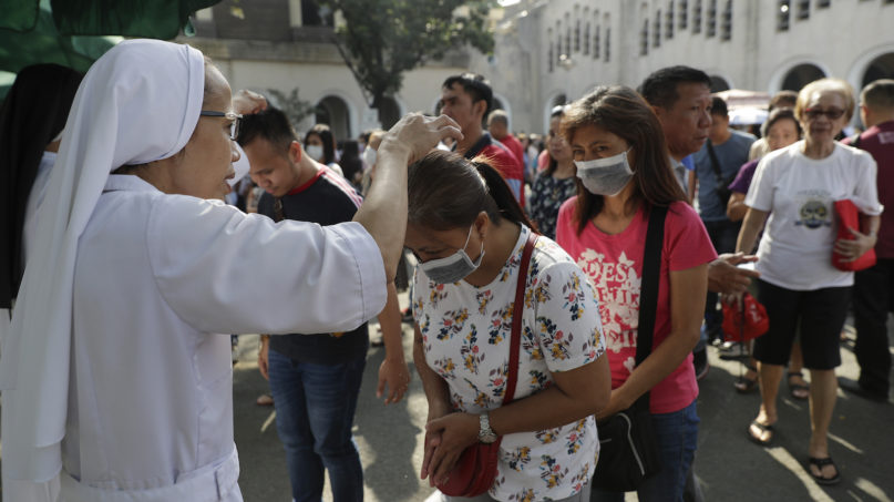 A Catholic nun sprinkles ash on the head of devotees wearing protective masks during Ash Wednesday rites Feb. 26, 2020, in Paranaque, metropolitan Manila, Philippines. Sprinkling ash on the head of devotees instead of using it to mark foreheads with a cross is one way to avoid physical contact during the pandemic. (AP Photo/Aaron Favila)