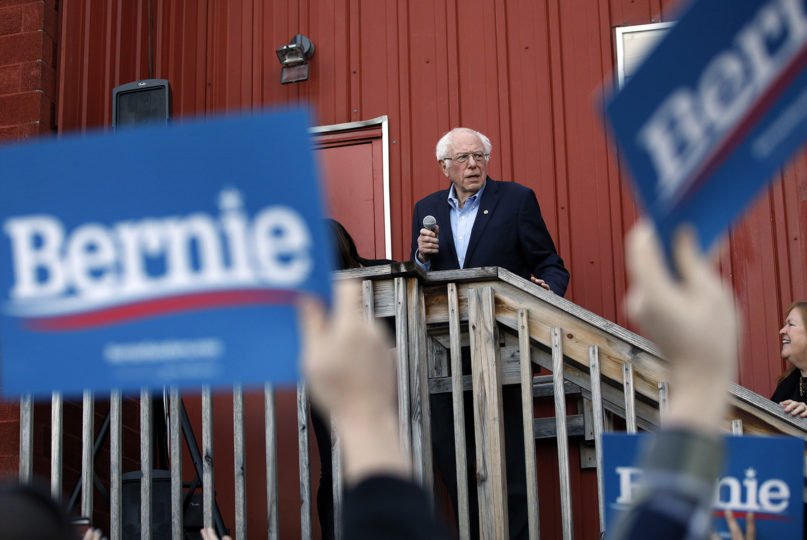 Democratic presidential candidate Sen. Bernie Sanders, I-Vt., accompanied by his wife Jane O'Meara Sanders, right, speaks to an overflow crowd at a Super Bowl watch party campaign event, Sunday, Feb. 2, 2020, in Des Moines, Iowa. (AP Photo/John Locher)