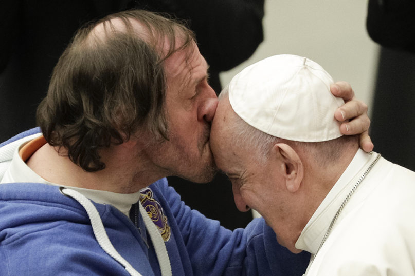 Pope Francis is kissed by a man during his weekly general audience, at the Pope Paul VI hall, at the Vatican, Wednesday, Feb. 19, 2020. (AP Photo/Andrew Medichini)