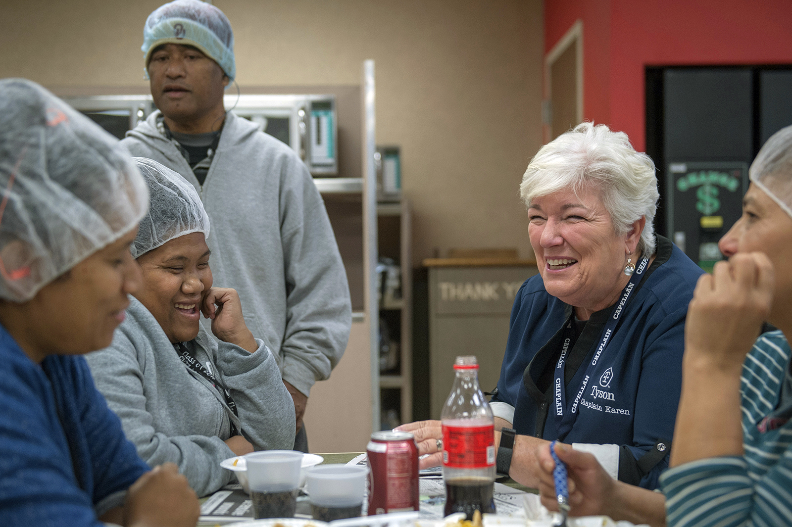Karen Diefendorf, second right, director of Chaplain Services at Tyson Foods, talks with employees at the company's Berry St. poultry plant in October 2018 in Springdale, Arkansas. The company deploys a team of more than 90 chaplains to comfort and counsel employees at its plants and offices. The program began in 2000. (Logan Webster/Tyson Foods via AP)