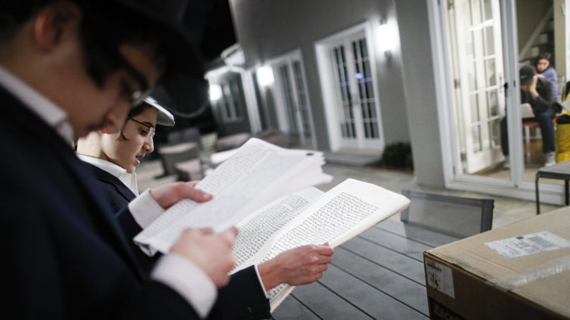 Yirmeyahu Gourarie, second from left, performs a socially distanced Purim reading from the Book of Esther for residents under self-quarantine due to potential exposure to the coronavirus, March 9, 2020, in New Rochelle, New York. (AP Photo/John Minchillo)