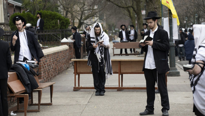 Orthodox Jewish men attempt to use social distancing as they pray outside the Chabad Lubavitch World Headquarters on March 20, 2020, in the Brooklyn borough of New York, before leaders of six major organizations in their faith released a joint statement urging worshippers to “avoid, to the maximum extent feasible, any outside interactions” to help stop the coronavirus pandemic. Orthodox Jewish leaders mounted their show of unity to underscore to a wide swath of congregants the importance of behavioral changes that amount to a massive upheaval in their faith communities. (AP Photo/Mark Lennihan)