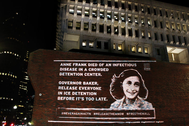An image of Anne Frank is projected with a message near the John F. Kennedy Federal Building in Boston on March 22, 2020, by the activist group Never Again Action. Photo courtesy of Never Again Action